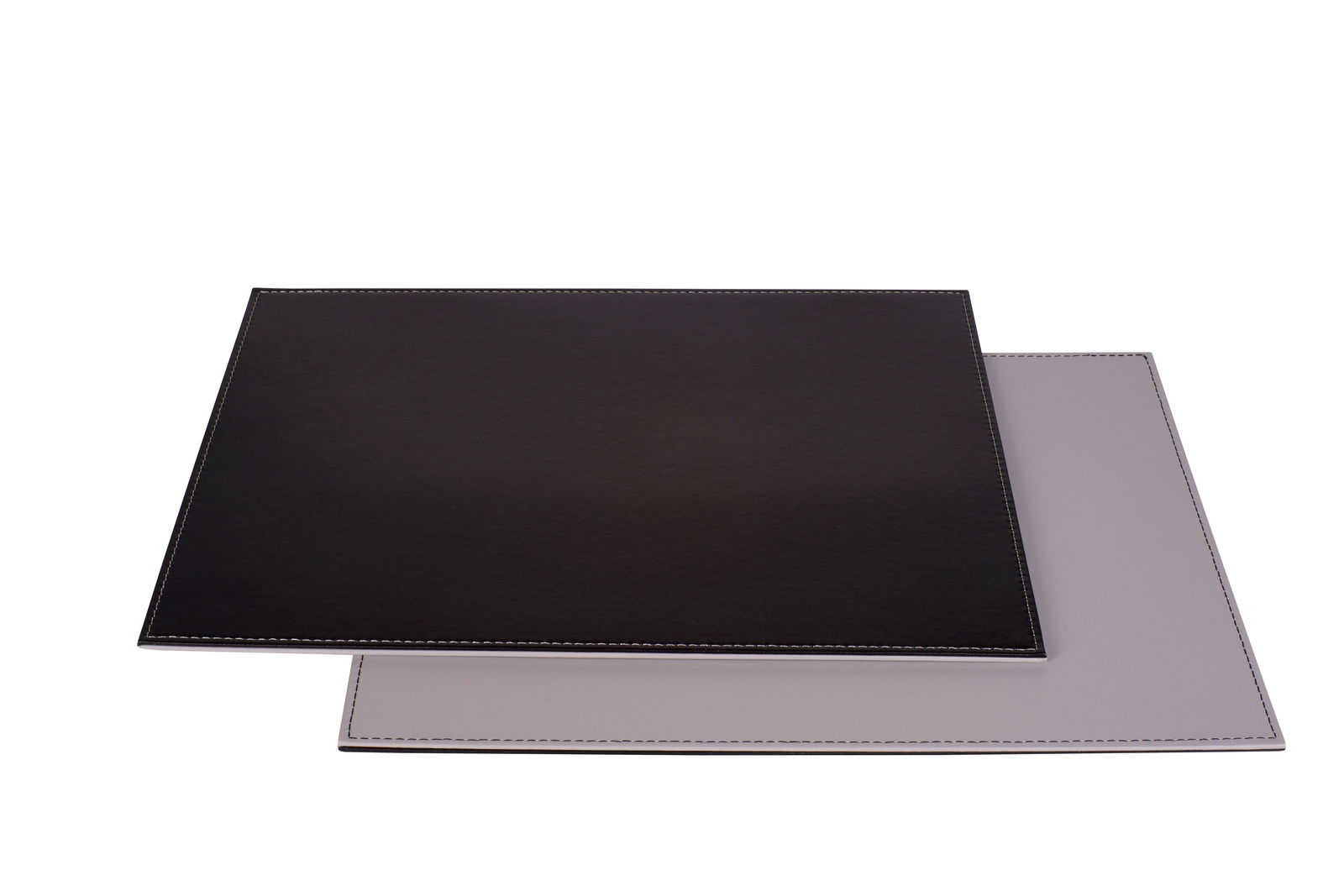 Zwei rechteckige Platzsets in Schwarz und Grau, übereinander gestapelt, aus einer leicht erhöhten Perspektive fotografiert.