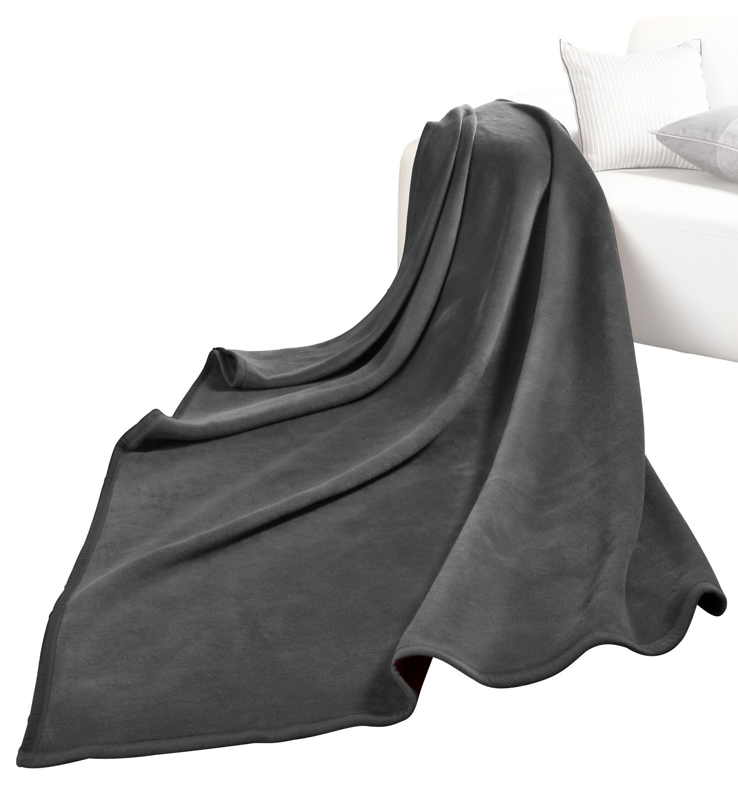Graue Wohndecke THERMOSOFT UNI auf einem weißen Sofa drapiert, Perspektive von vorne