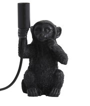 Schwarze Tischleuchte in Form eines sitzenden Affen, der eine Lampenfassung in der Hand hält. Frontalansicht.