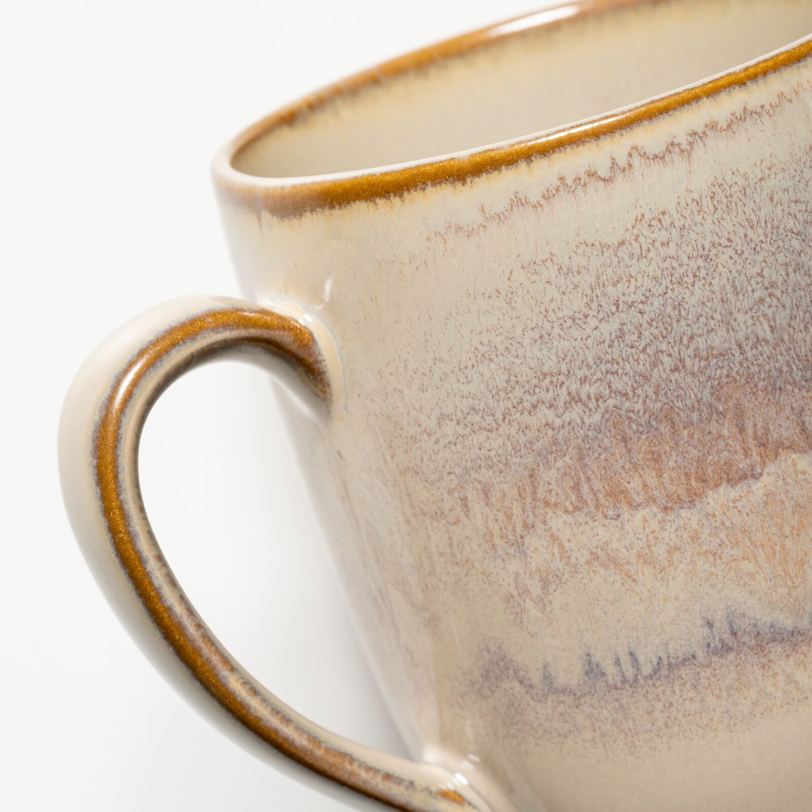 Nahaufnahme einer beigefarbenen Keramik-Kaffeetasse mit braunem Rand und Henkel, seitliche Perspektive vor weißem Hintergrund