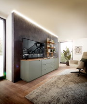 Modernes Wohnzimmer mit stilvollem Wandpaneel, das hinter einem TV und einem Sideboard mit Schubladen angebracht ist. Perspektive von der Seite, die den Raum und die Einrichtung zeigt.