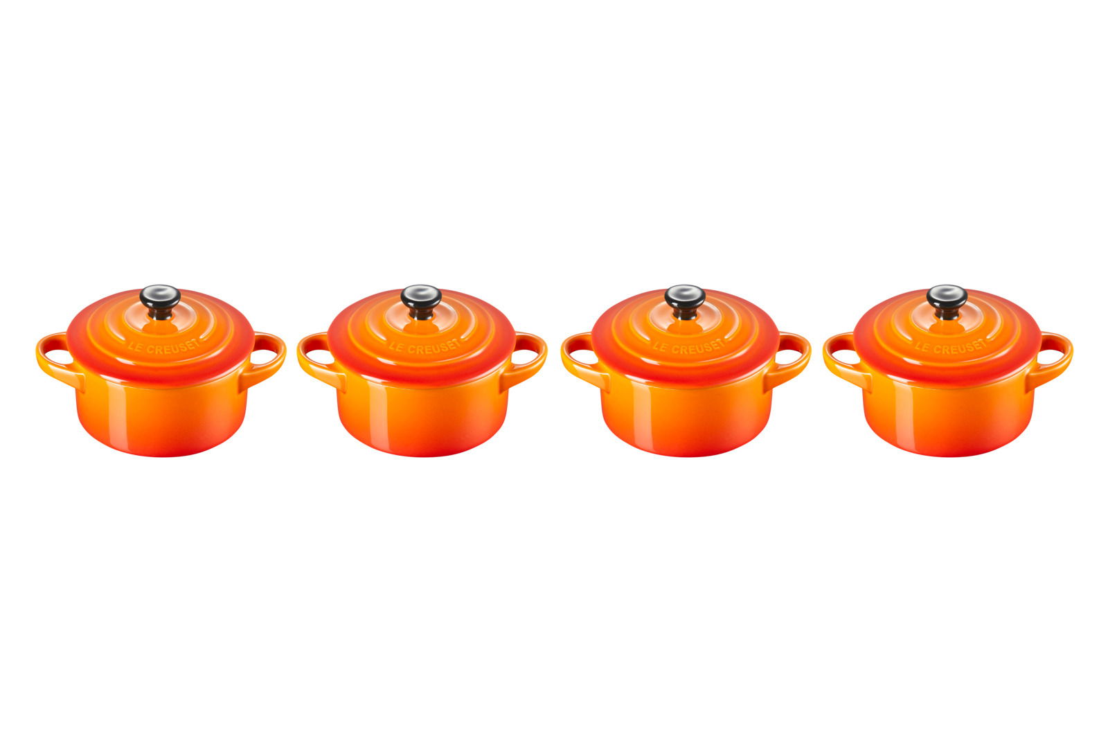 LE CREUSET Mini-Cocotte 4er-Set 10cm Ofenrot Vier ofenrote Mini-Cocottes von oben betrachtet, gleichmäßig nebeneinander angeordnet.