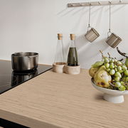 Moderne Küchenarbeitsplatte mit Induktionskochfeld, Topf, Ölflaschen und Obstschale mit Trauben und Birnen, seitliche Perspektive.