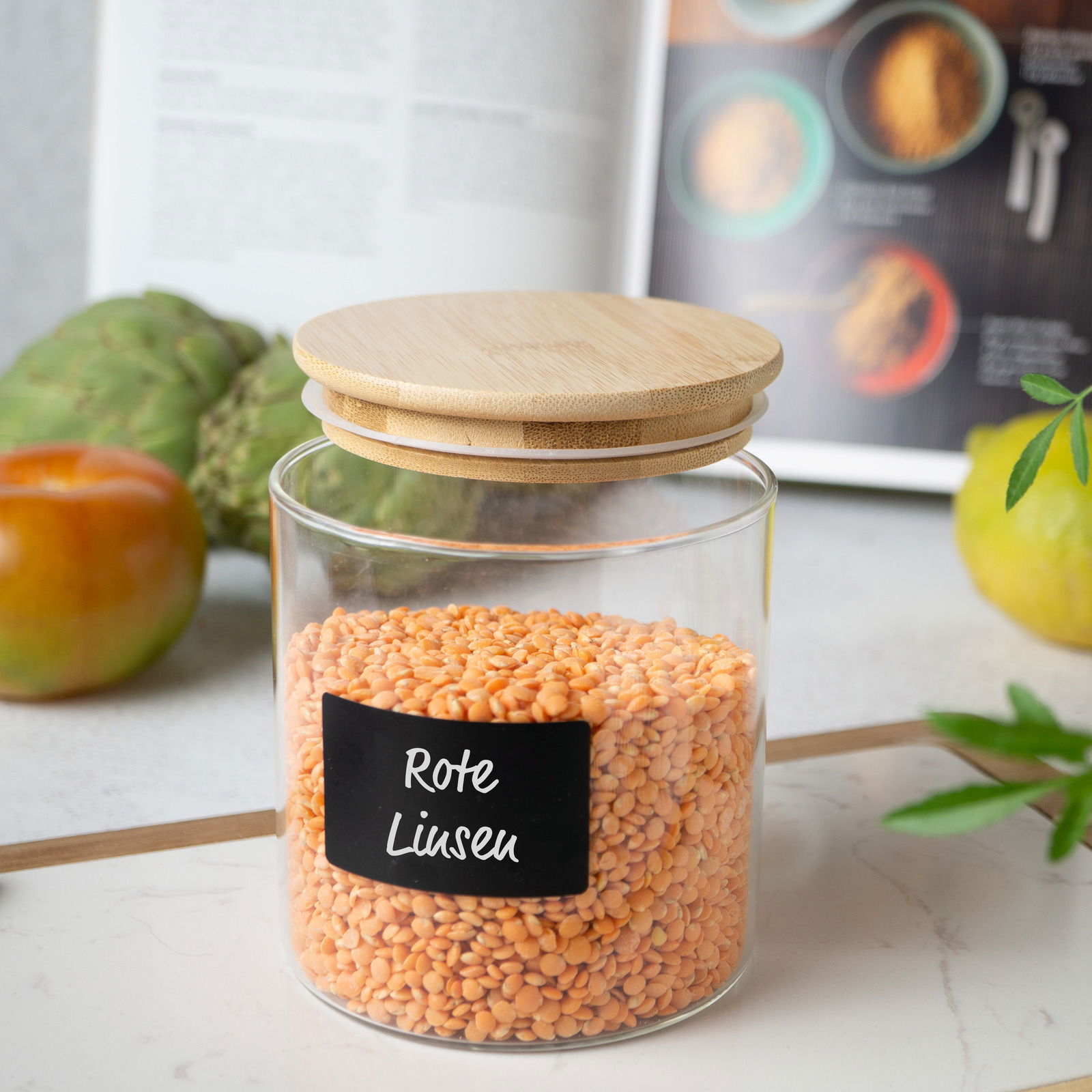 Vorratsglas mit Bambusdeckel, gefüllt mit roten Linsen, aus seitlicher Perspektive fotografiert.
