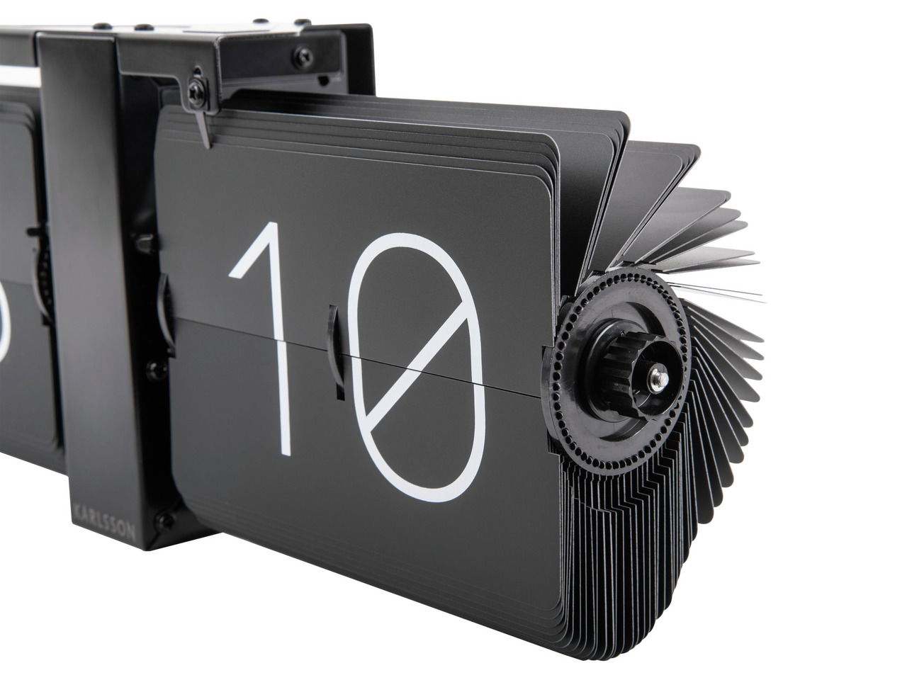 Nahaufnahme einer modernen, schwarzen Wanduhr ohne Gehäuse mit Flip-Mechanismus, die die Zahl 10 anzeigt. Perspektive von der Seite.