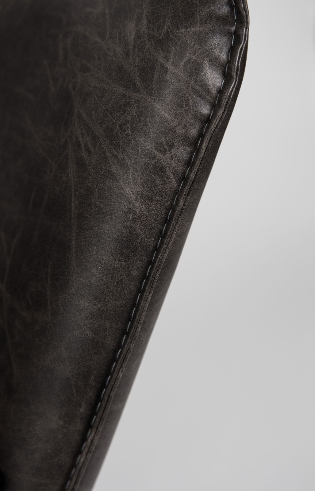 Nahaufnahme der Naht eines Sessels aus dunkelbraunem Leder, seitliche Perspektive