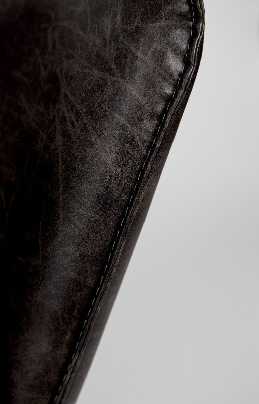 Nahaufnahme der Naht eines Sessels aus dunkelbraunem Leder, seitliche Perspektive