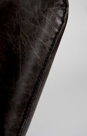 Nahaufnahme der Naht eines Sessels aus dunkelbraunem Leder, seitliche Perspektive