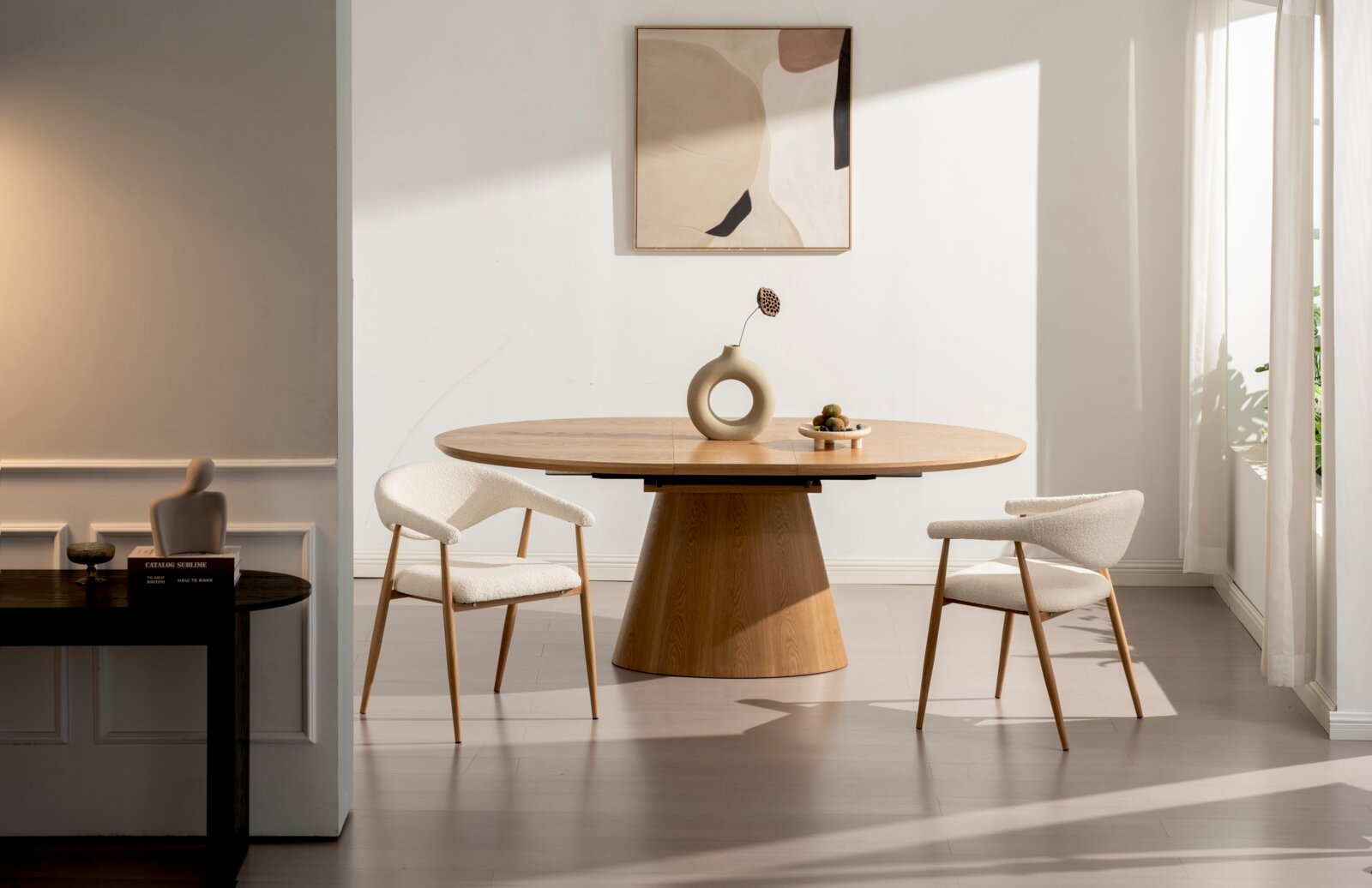Ovaler Esstisch aus hellem Holz mit konischem Mittelfuß, dekoriert mit Vase und Schale, in modernem, lichtdurchflutetem Esszimmer frontale Perspektive auf Tisch und Stühle