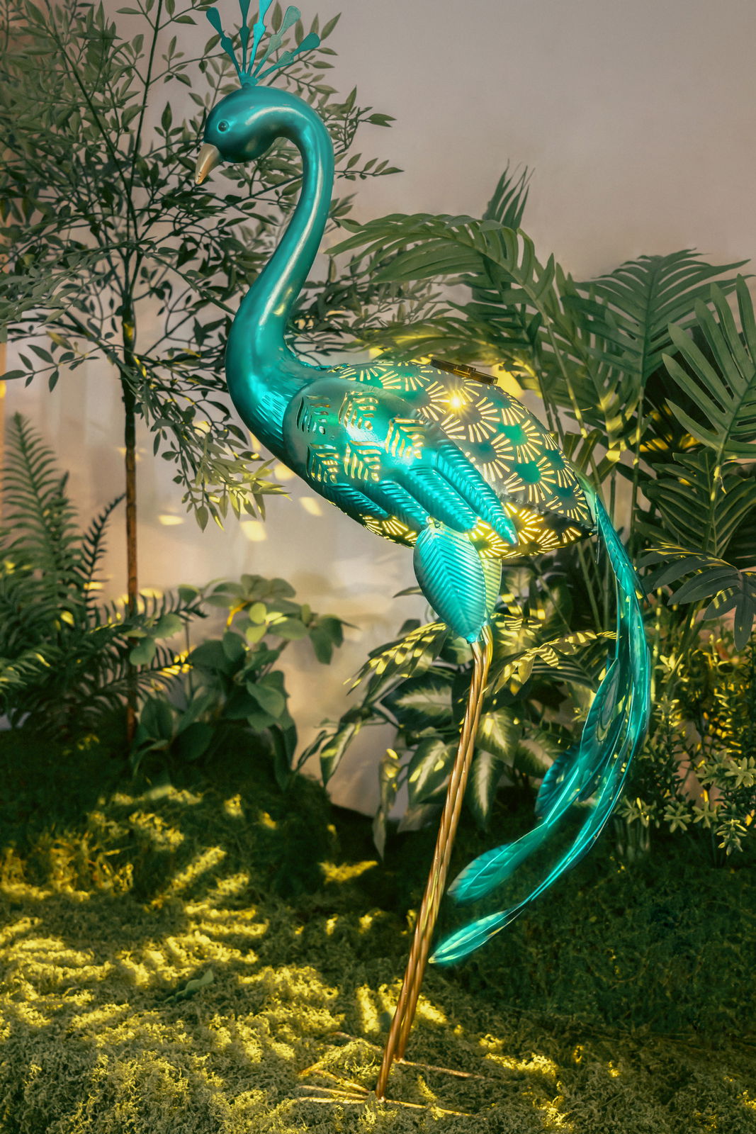 Dekorative Solarleuchte in Form eines Pfaus, seitliche Perspektive, umgeben von Pflanzen.