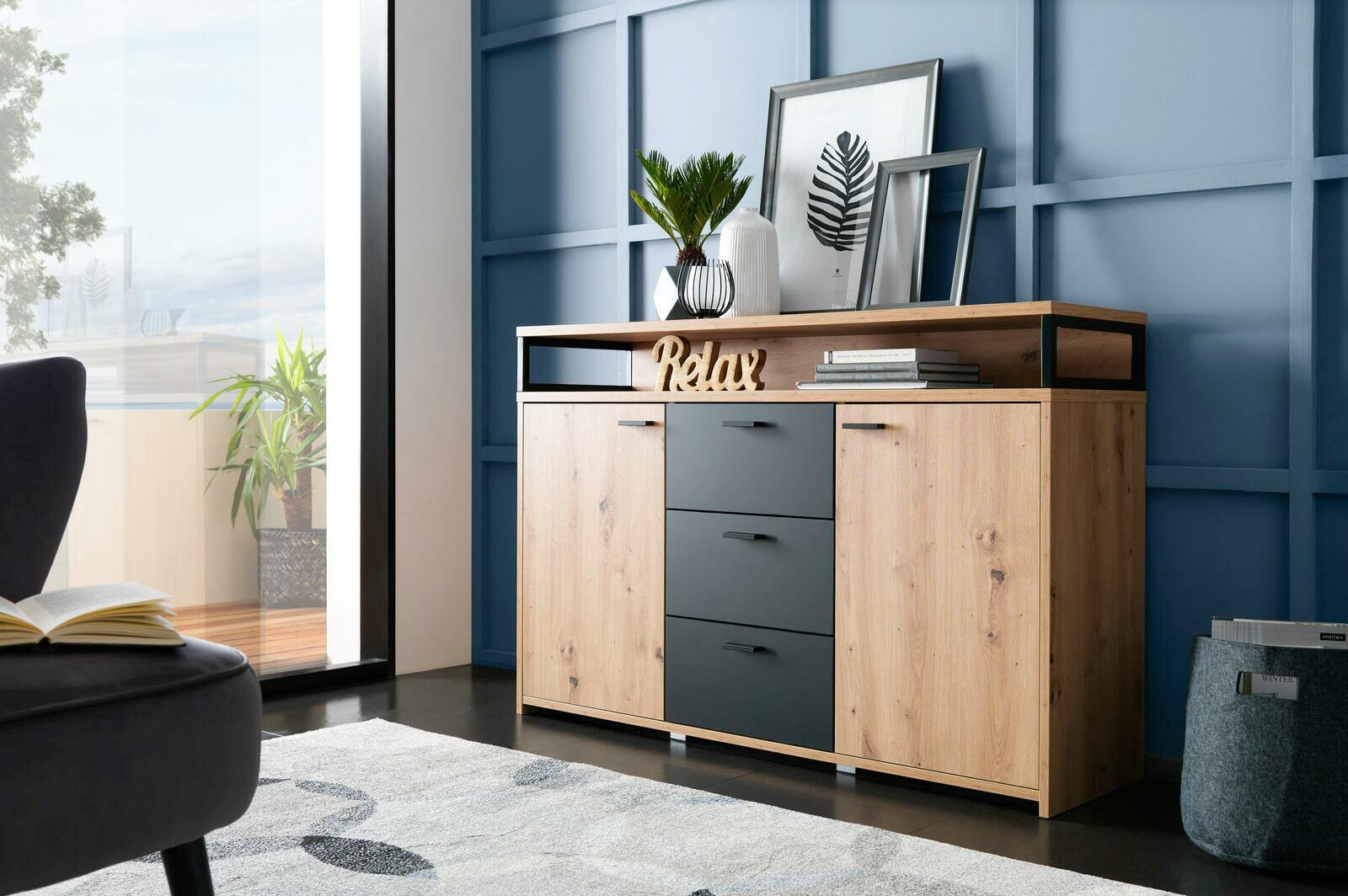Modernes Sideboard aus Holz mit drei Schubladen und zwei Türen, dekoriert mit Pflanzen und Bildern, seitliche Perspektive.