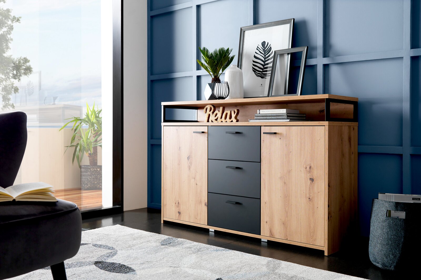 XORA Sideboard LIFE Modernes Sideboard aus Holz mit drei Schubladen und zwei Türen, dekoriert mit Pflanzen und Bildern, seitliche Perspektive.