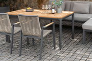 Zwei moderne Stapelsessel aus Metall und Geflecht, seitliche Perspektive, an einem Holztisch im Freien aufgestellt.