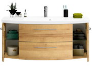 Frontale Ansicht eines modernen Waschtischs mit Holzoptik, zwei Schubladen und offenen Seitentüren, dekoriert mit Pflanzen, Handtüchern und Pflegeprodukten.