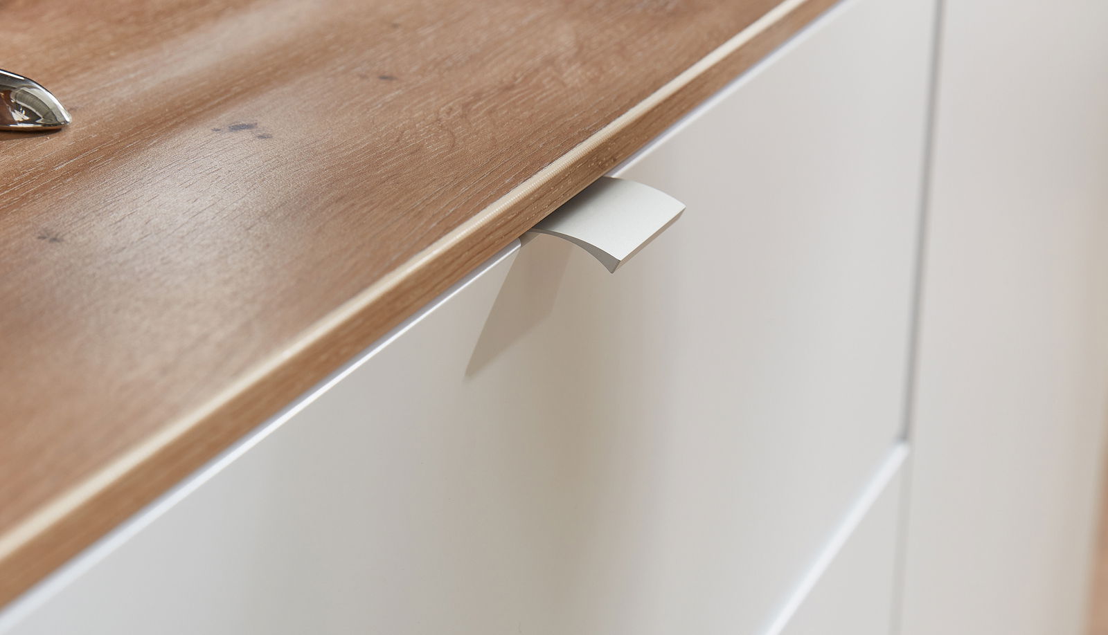 Nahaufnahme eines TV-Sideboards mit Holzoberfläche und weißer Schublade, seitliche Perspektive