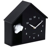 Schwarze Wanduhr in Form eines Hauses mit einem weißen Hundekopf, seitliche Perspektive