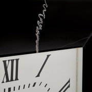 Nahaufnahme einer Wanduhr mit römischen Ziffern und einem schwarzen Rahmen, aus seitlicher Perspektive.