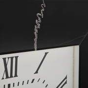 Nahaufnahme einer Wanduhr mit römischen Ziffern und einem schwarzen Rahmen, aus seitlicher Perspektive.