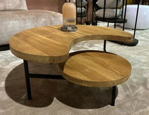 Moderner Couchtisch aus Holz mit organischer Form und zwei Ebenen, seitliche Perspektive.