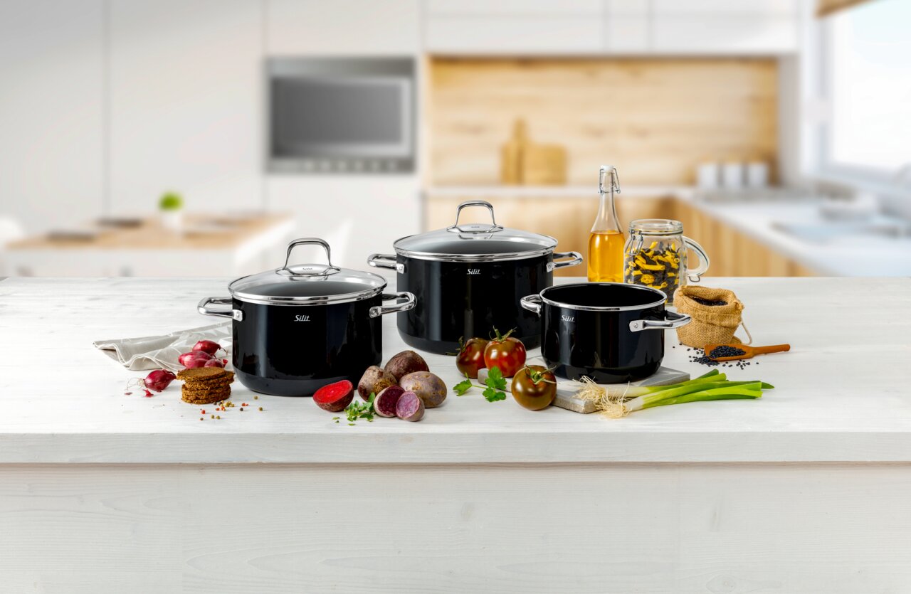 Topfset Elegance Line 4-teilig in einer modernen Küche, frontal fotografiert, umgeben von frischen Zutaten wie Tomaten, Zwiebeln und Gewürzen.
