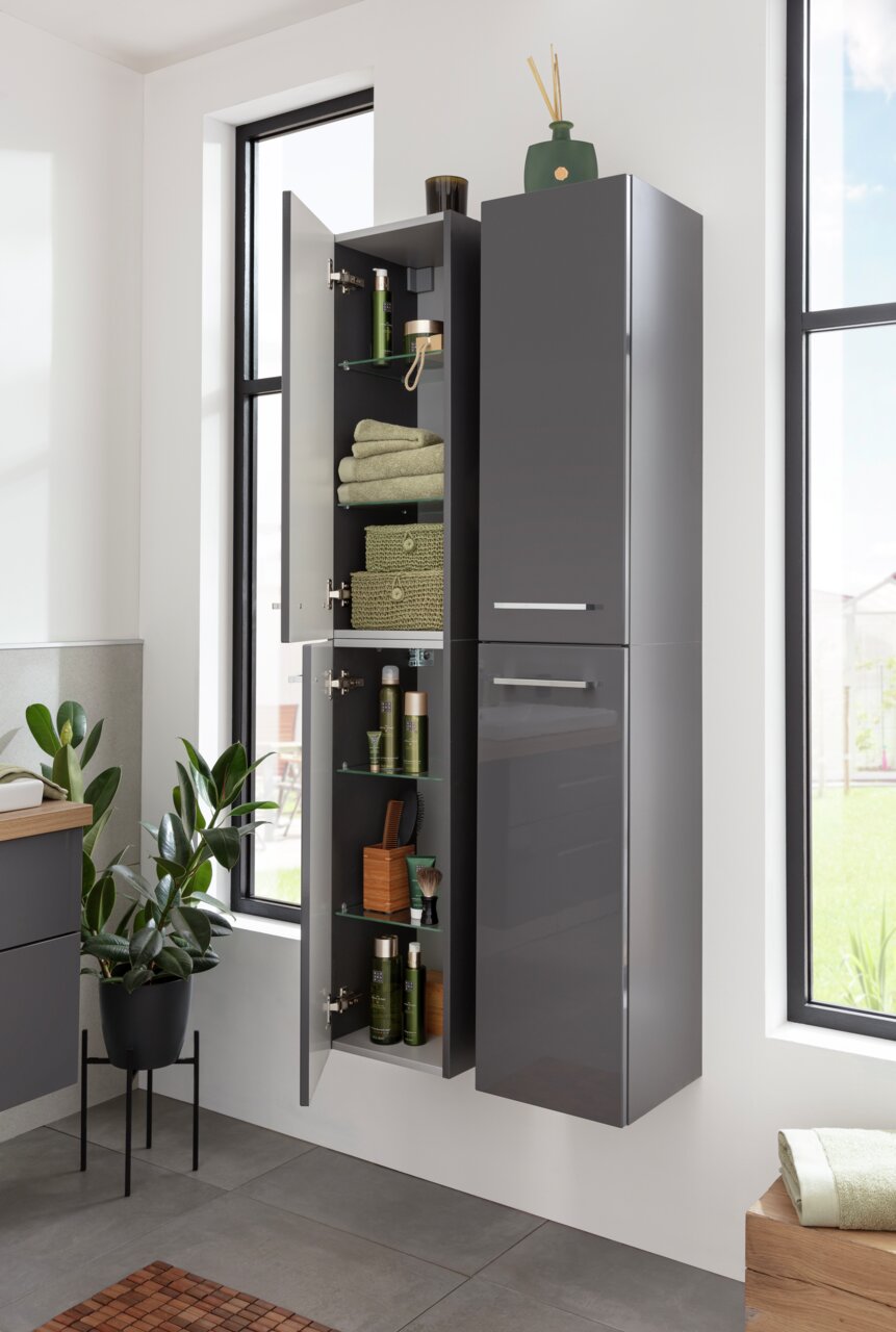 Moderner, grauer Hochschrank in einem Badezimmer, teilweise geöffnet, mit Handtüchern und Pflegeprodukten gefüllt. Perspektive von vorne.