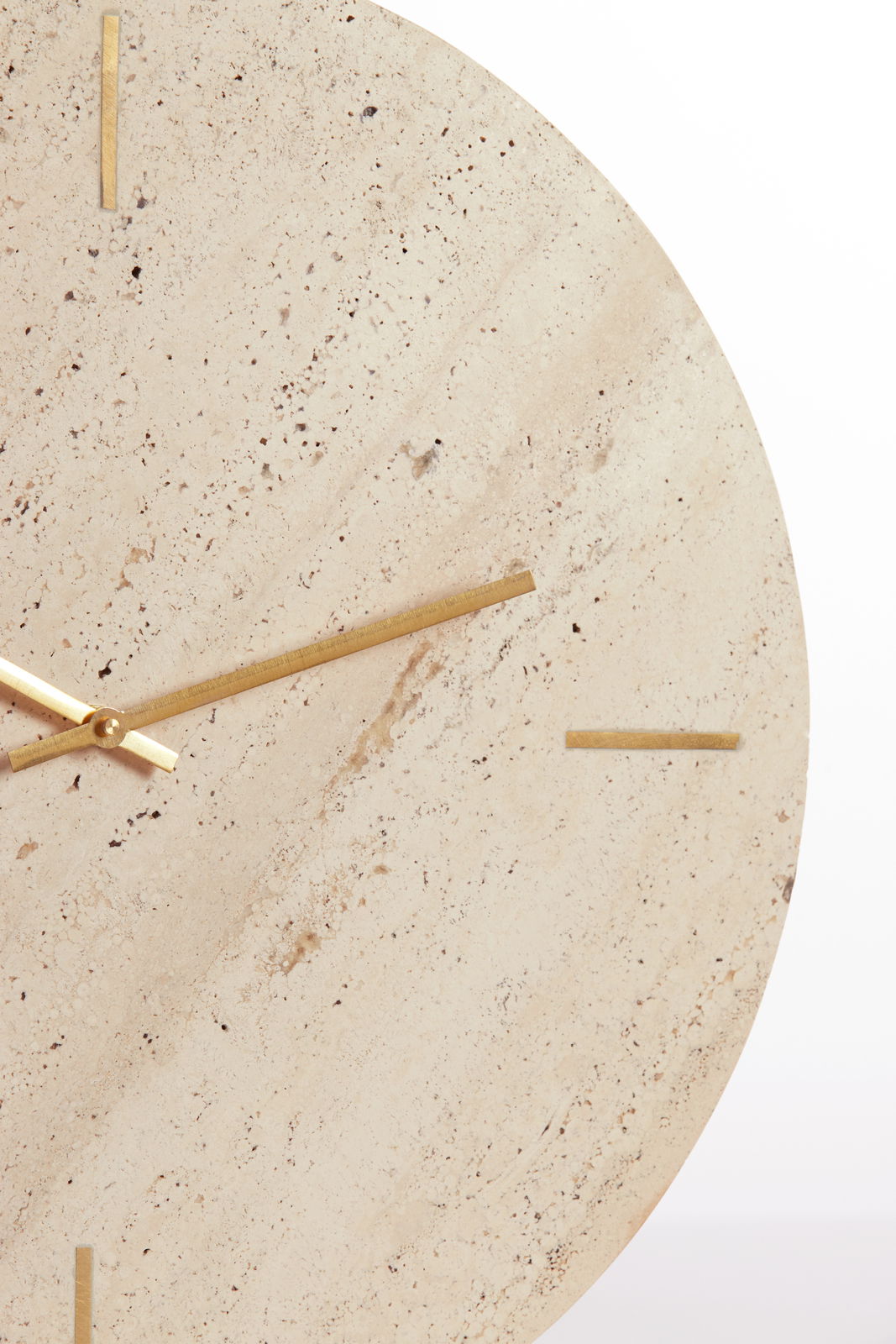 Nahaufnahme einer eleganten Uhr mit einem Zifferblatt aus hellem Naturstein und goldenen Zeigern, frontal betrachtet.