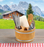 Holz-Besteckbehälter aus Kiefer mit Besteck und Servietten, auf einem Tisch mit Alpenhütte im Hintergrund, Vorderansicht