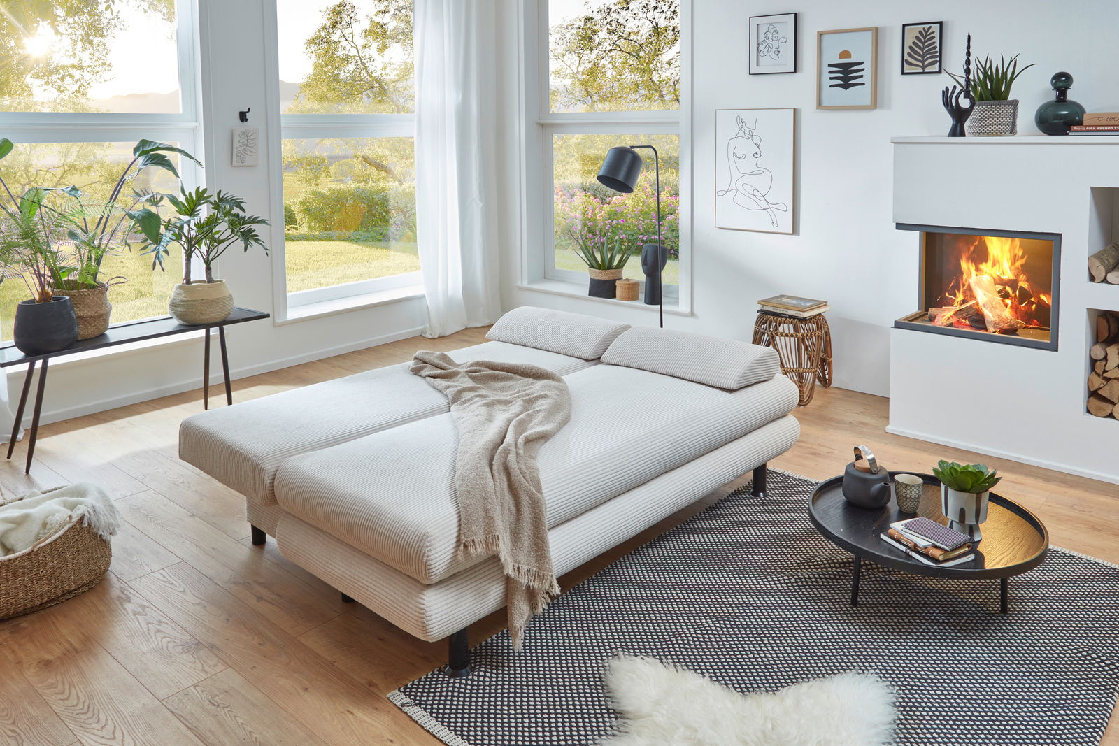 Modernes Funktionssofa Bern in einem gemütlichen Wohnzimmer mit Kamin, aus der Perspektive von vorne links fotografiert.