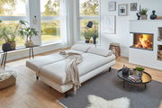 Modernes Funktionssofa Bern in einem gemütlichen Wohnzimmer mit Kamin, aus der Perspektive von vorne links fotografiert.