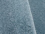 Nahaufnahme eines blauen Uni-Teppichs mit weicher, flauschiger Textur, seitliche Perspektive