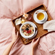 Ontbijtblad met een schaaltje muesli, een kopje thee en een klein melkkannetje, van bovenaf gefotografeerd.