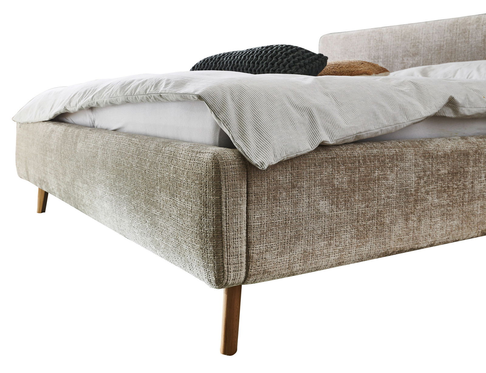 Nahaufnahme eines Polsterbetts in Beige mit Holzfüßen, seitliche Perspektive