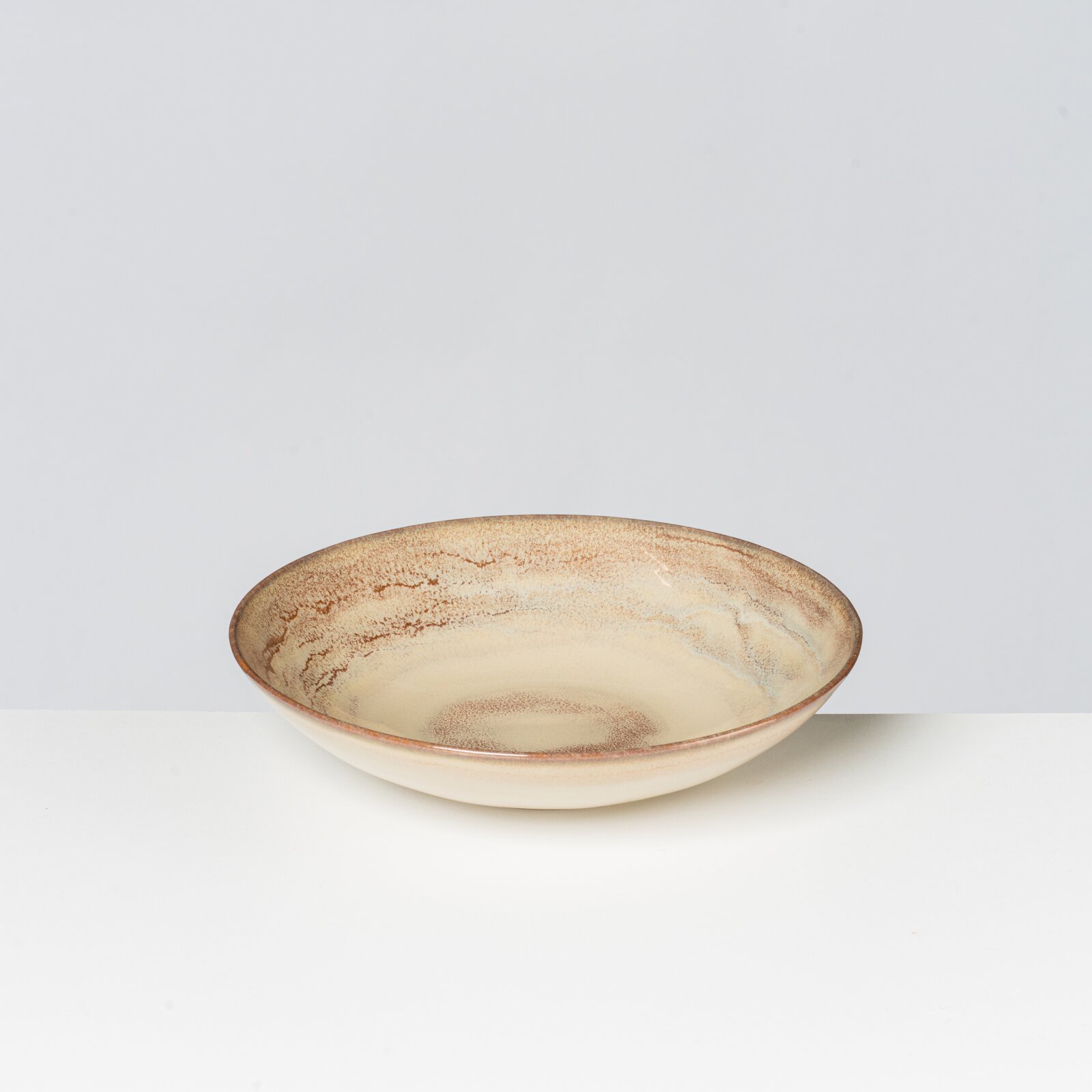 Beige-weiß glasierte Keramikschale mit braun gesprenkeltem Rand, frontal aus leicht erhöhter Perspektive fotografiert.