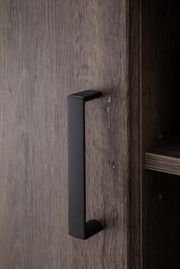 Nahaufnahme eines schwarzen Griffs an einer Holztür eines Sideboards, seitliche Perspektive