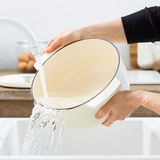 Gusseisen Bräter Oval 30 cm von KitchenAid, in der Küche beim Ausgießen von Wasser in ein Waschbecken, seitliche Perspektive.