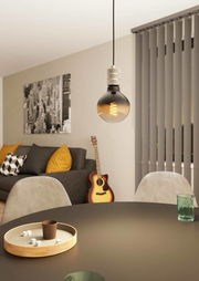 Moderne Pendelleuchte YORTH in einem stilvollen Wohnzimmer, im Vordergrund ein runder Tisch mit Würfeln und einem Becher, im Hintergrund ein Sofa mit Kissen und eine Gitarre. Perspektive von unten auf die Lampe.