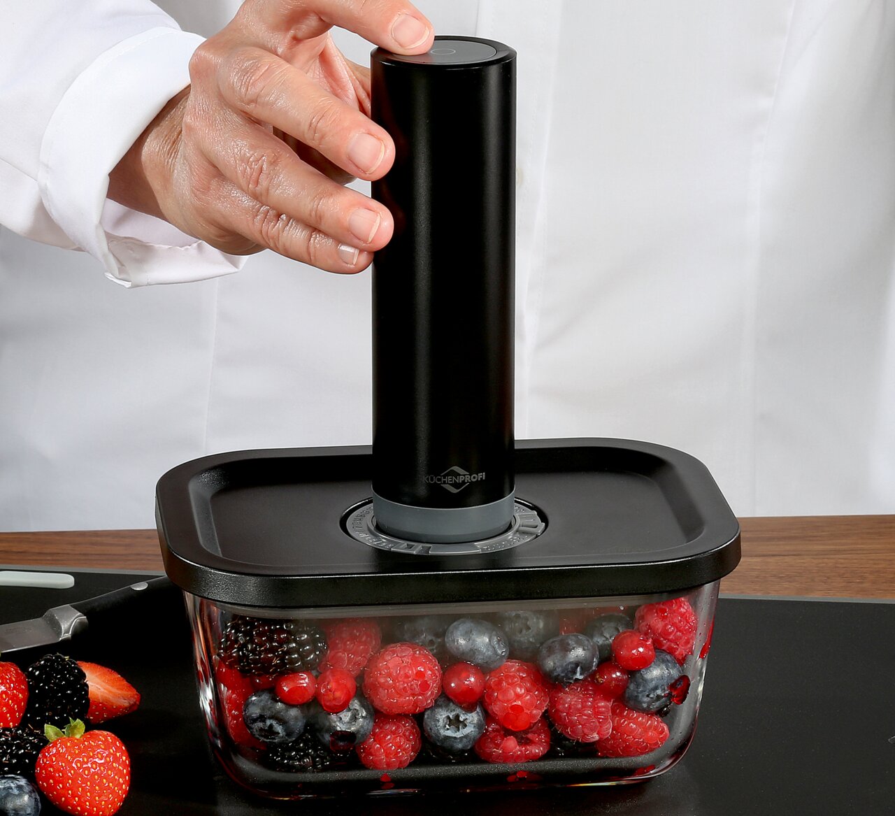 Vakuumier-Set EASYFRESH in seitlicher Perspektive, mit Hand, die das Gerät auf einem Behälter mit Beeren bedient.