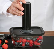Vakuumier-Set EASYFRESH in seitlicher Perspektive, mit Hand, die das Gerät auf einem Behälter mit Beeren bedient.