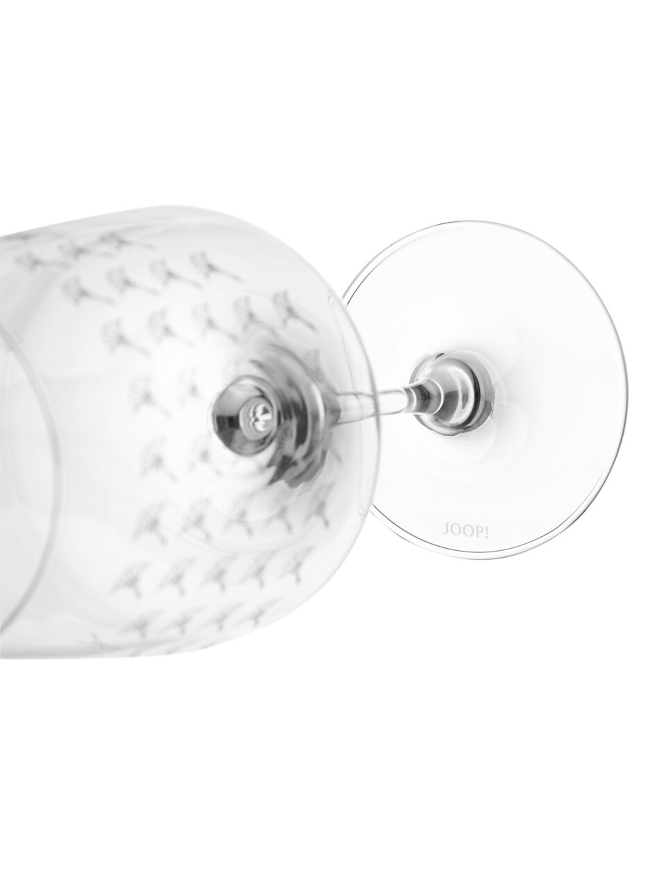 Nahaufnahme eines Rotweinglases mit dekorativem Muster, liegend auf der Seite, mit Blick auf den Stiel und den Fuß des Glases.