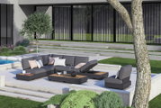 Moderne Outdoor-Lounge mit grauen Sitzmöbeln und Kaffeetischen auf einer Terrasse, umgeben von grüner Landschaft. Perspektive von schräg oben.