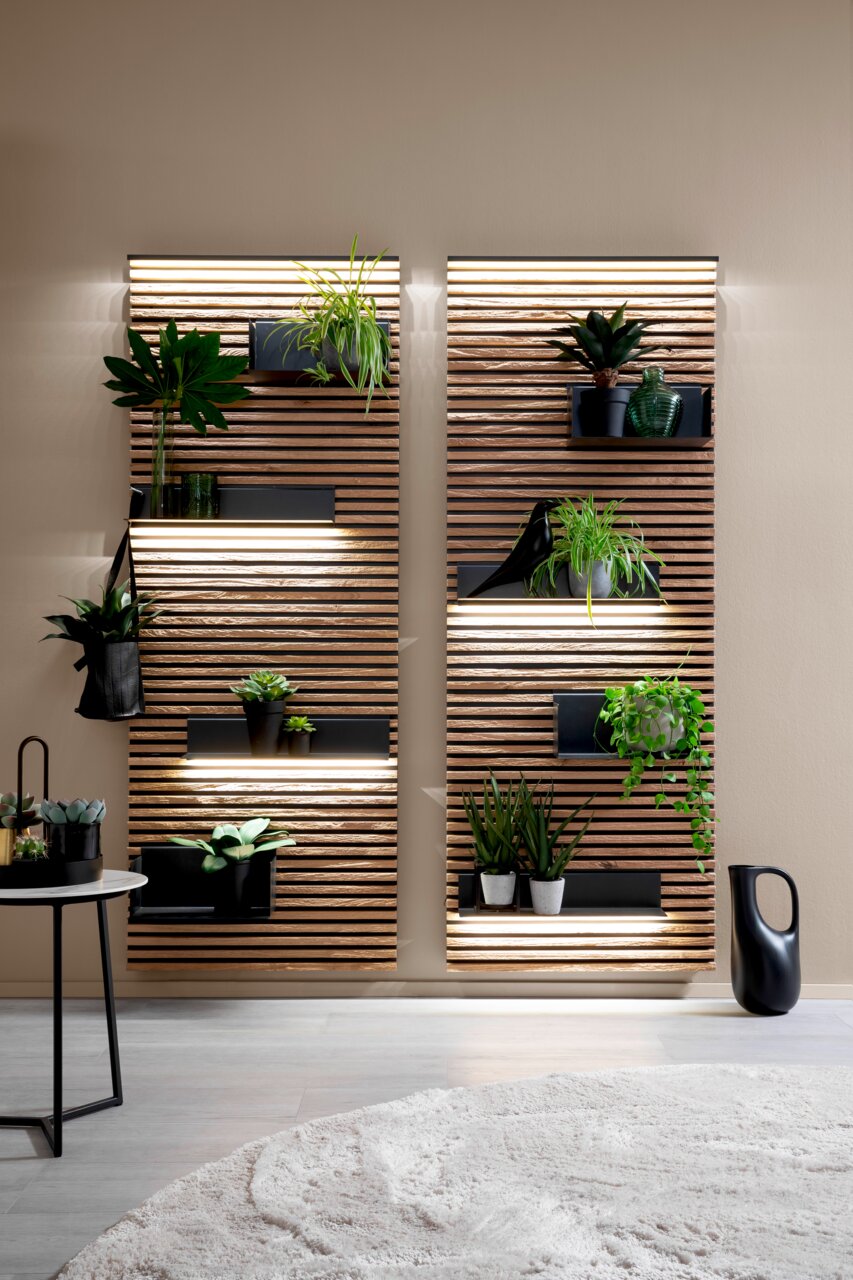 Lamellen-Paneel YONNA mit Pflanzen dekoriert, frontal betrachtet, mit integrierter Beleuchtung und modernen Regalen.