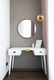 Runder Wandspiegel der Serie ESRA über einem weißen Schreibtisch mit goldenen Akzenten, seitliche Perspektive.