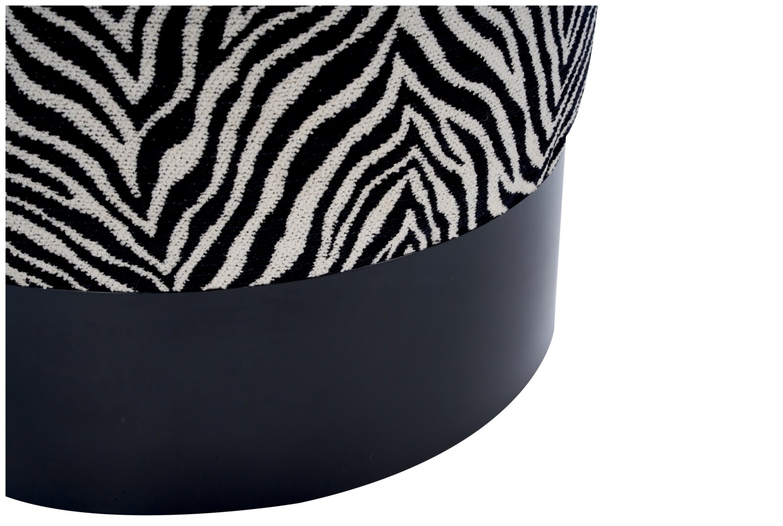 Detailfoto in schuin zijaanzicht van een ronde poef met stof met zwart-wit zebraprint en een matzwarte voet