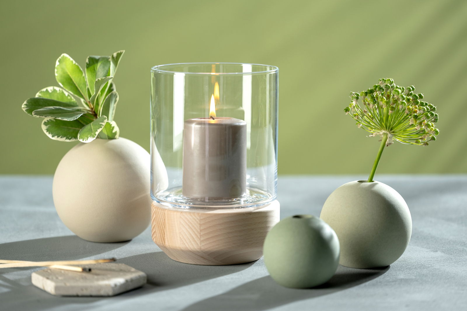 Keramikvase in Grün mit runder Form, dekoriert mit Pflanzen, aus seitlicher Perspektive fotografiert.