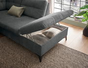 Graues Ecksofa mit hochgeklappter Sitzfläche, die Stauraum mit Kissen zeigt, aus der Vogelperspektive fotografiert.