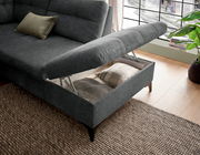 Graues Ecksofa mit hochgeklappter Sitzfläche, die Stauraum mit Kissen zeigt, aus der Vogelperspektive fotografiert.