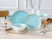 Türkises, gesprenkeltes Keramik-Geschirrset mit Teller und Schale auf gedecktem Tisch, frontal in leicht seitlicher Perspektive aufgenommen