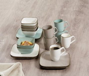 Kaffee-Set Casa 18-teilig, bestehend aus Tassen, Schalen und Tellern in sanften Pastelltönen, auf einer Holzoberfläche von oben fotografiert.
