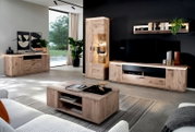 Moderne woonkamer met wandmeubel in eikenlook: tv-lowboard met ledverlichting, vitrinekast, dressoir en salontafel; perspectief: breedbeeldopname van voren, licht van links.