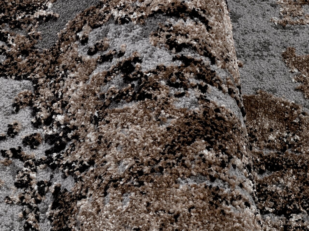 Nahaufnahme eines strukturierten Teppichs in Erdtönen mit einem gemusterten Design, perspektivisch von der Seite aufgenommen.